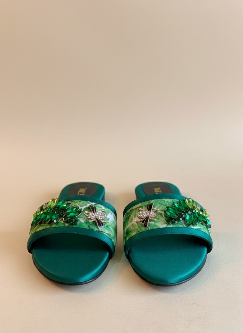 Pair of green sandals with decorative elements on a beige background