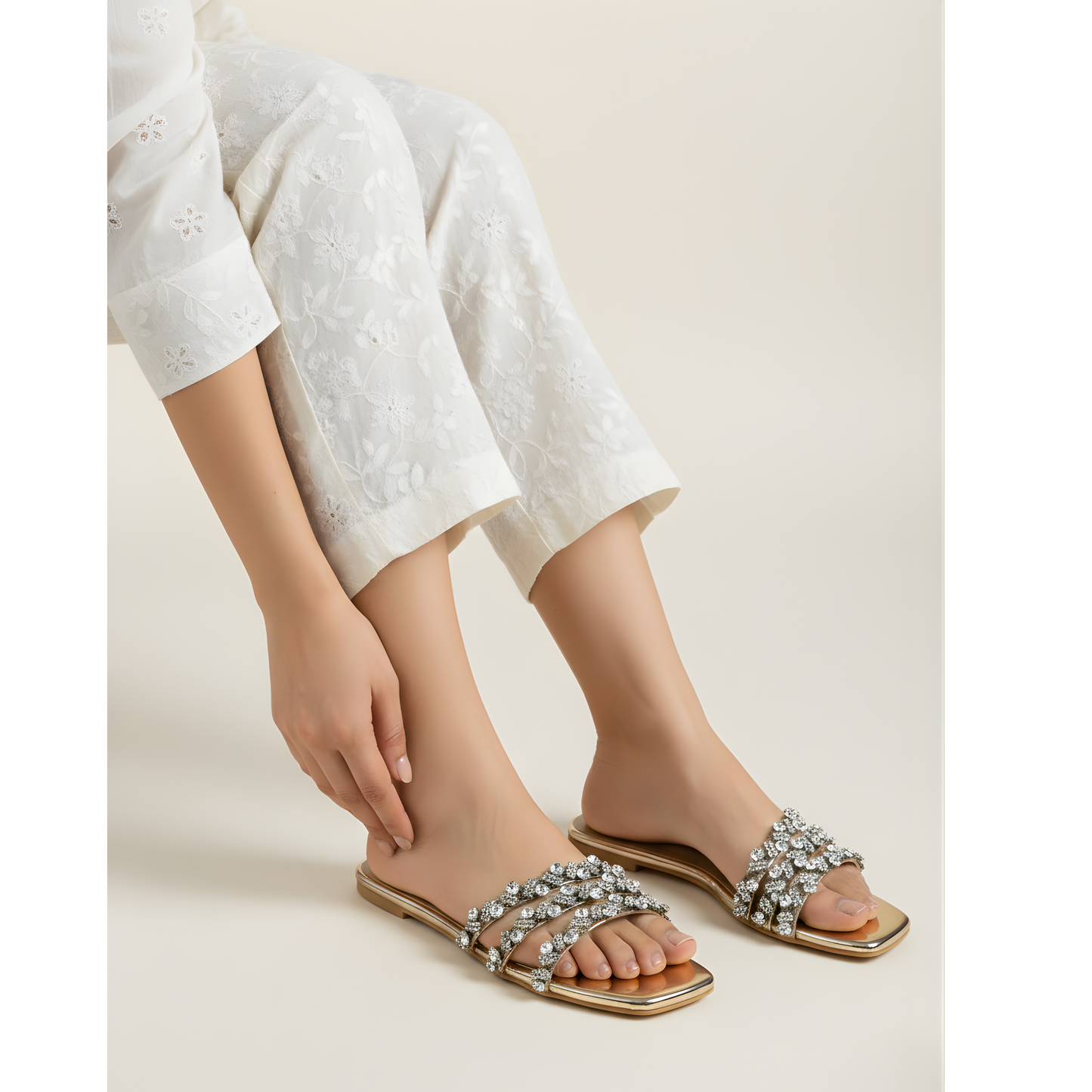 Person wearing embellished sandals on a plain background